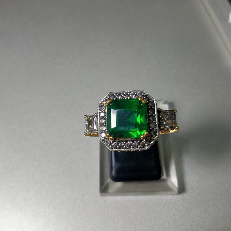 emerald cut emerald and diamond three stone ring with a two tone setting